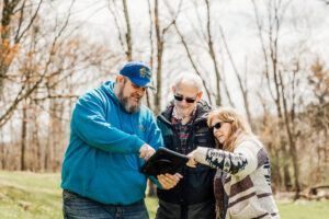 Planet Roof team member showing homeowners roofing project details on a tablet during an outdoor consultation.