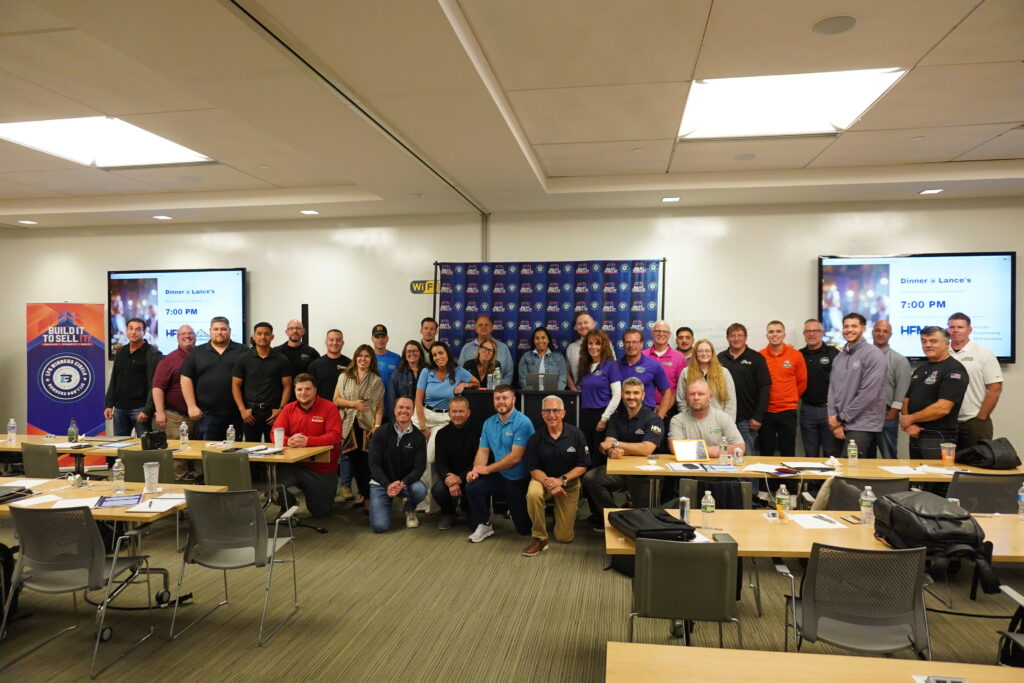 Large diverse group of home service business owners and operators posing together for a cohort photo inside a corporate classroom training facility.