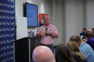 Lance Bachmann speaking into a microphone during a Winners Circle business training session.