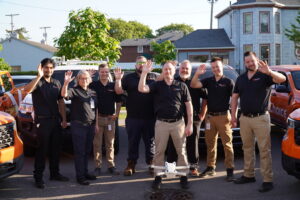 Members of the Tru Choice Roofing team standing together in branded corporate shirts alongside their service vehicles for a corporate culture feature.